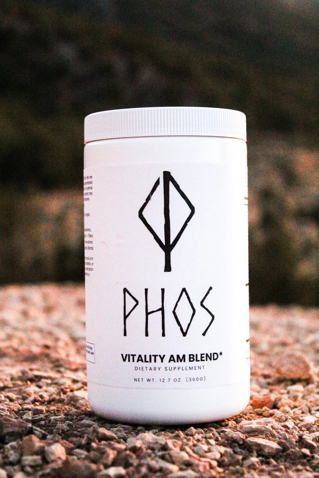 Phos vitality AM blend dietary supplement container placed outdoors on gravel ground