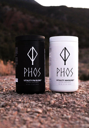 Phos AM and PM dietary supplement containers outdoors on rocky ground